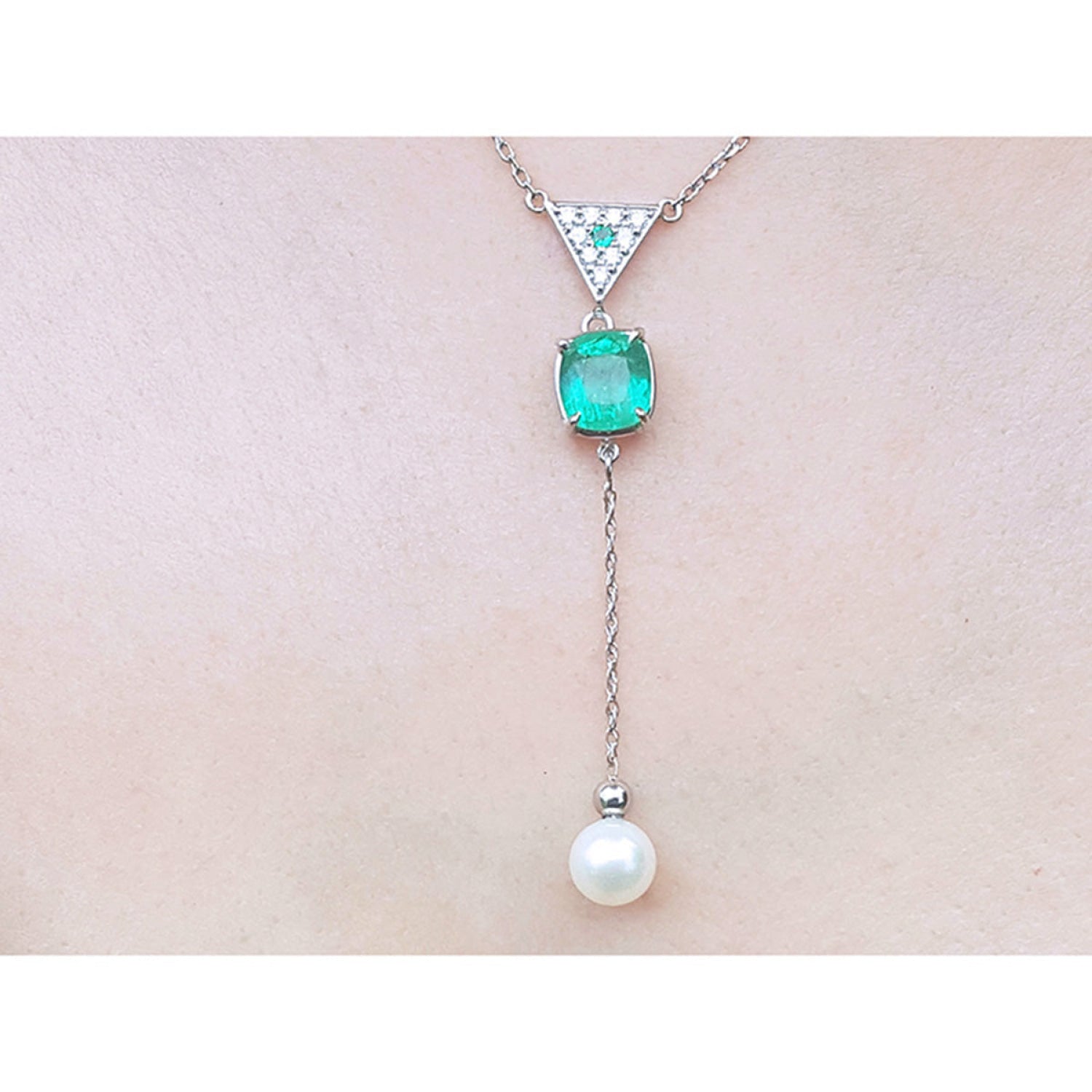 14K white gold necklace with emerald cushion cut, diamond triangle, and hanging white pearl.