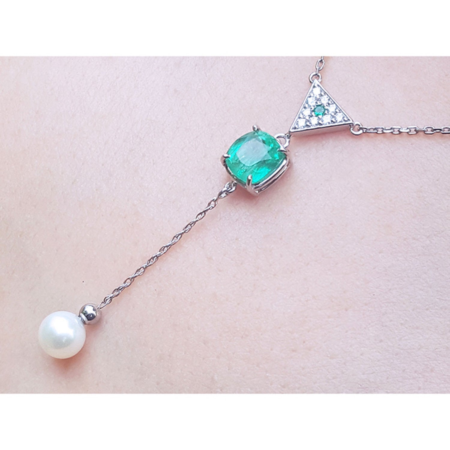 14K white gold necklace with cushion-cut emerald, diamond triangle cluster, and dangling freshwater pearl.