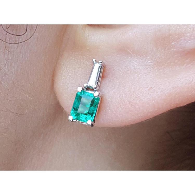 close-up of a Colombian emerald and baguette diamond stud earring on an earlobe.
