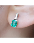 close-up of a Colombian emerald and baguette diamond stud earring on an earlobe.