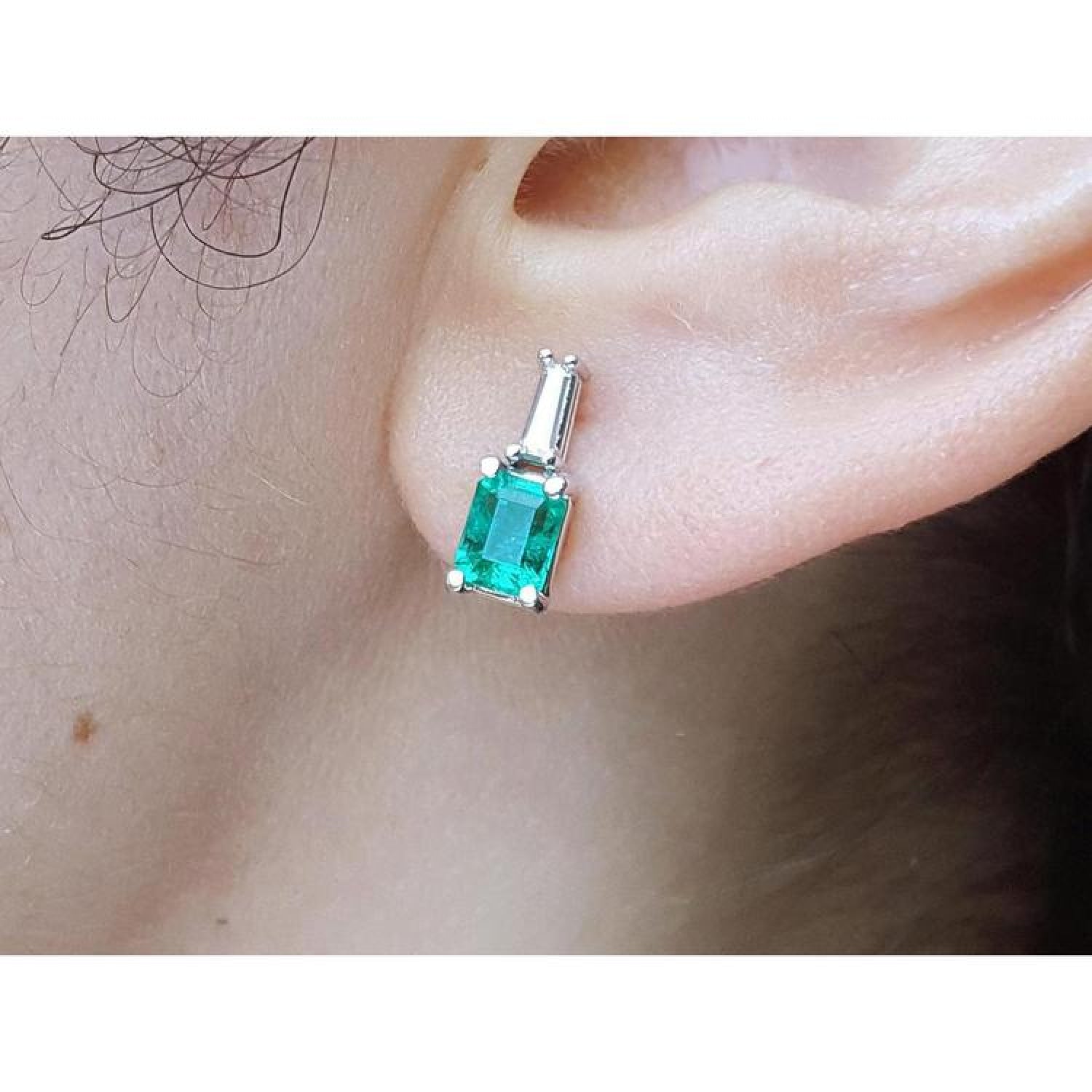Colombian emerald and baguette diamond stud earrings, 14K white gold, on an ear.