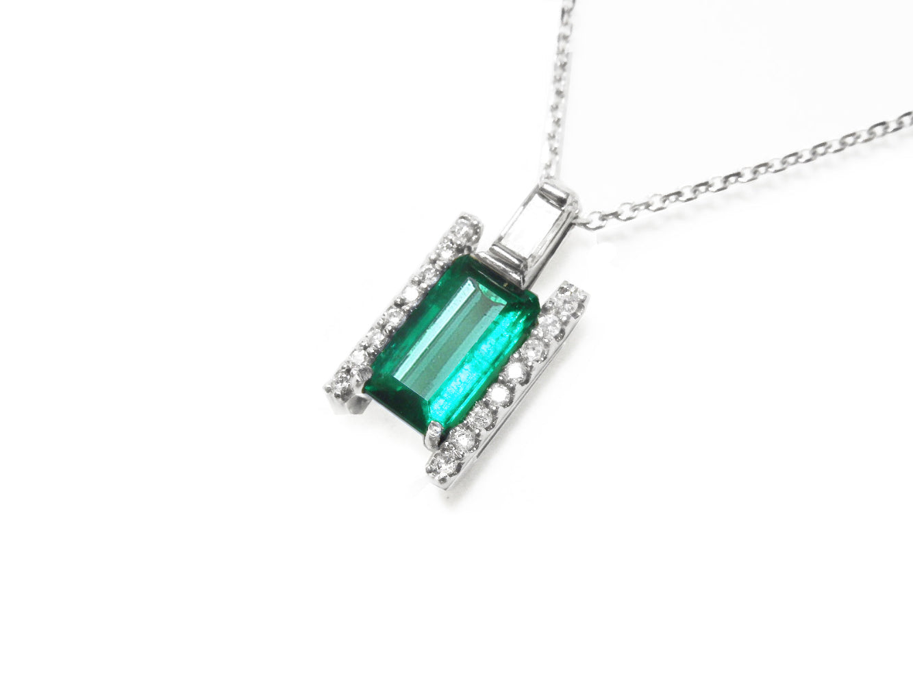 This emerald and baguette diamond pendant necklace is displaying the topside view.