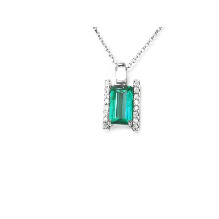 A natural emerald gemstone pendant with diamond accents on each side in white gold.