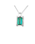 A natural emerald gemstone pendant with diamond accents on each side in white gold.