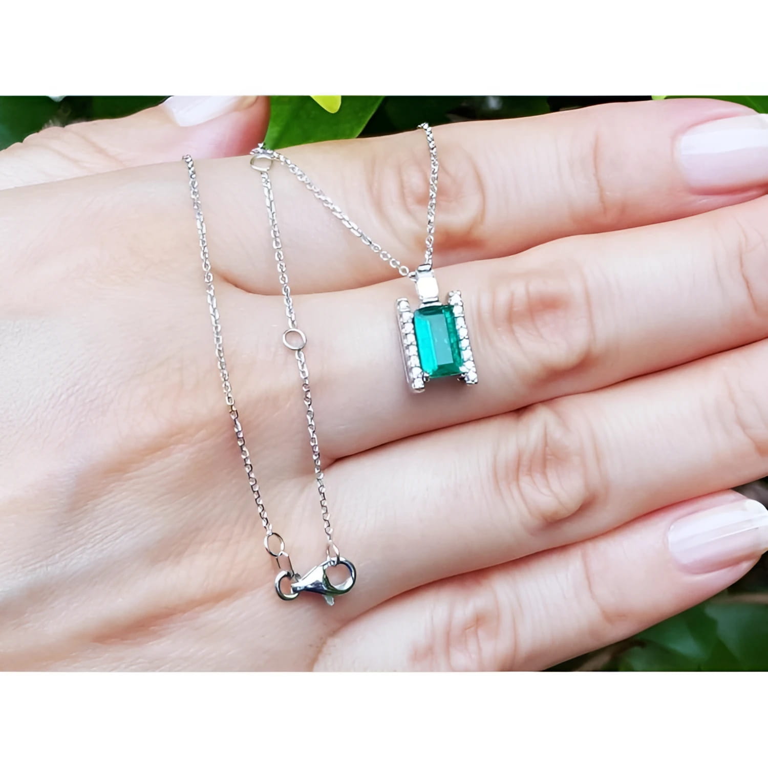 0.75 ct. baguette emerald and diamond pendant necklace in 14K white gold, worn on a hand.