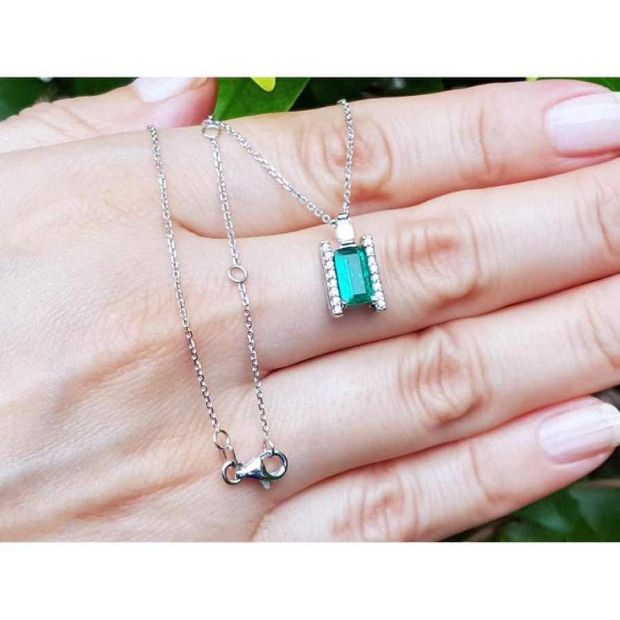 0.75 ct. baguette emerald and diamond pendant necklace in 14K white gold, worn on a hand.