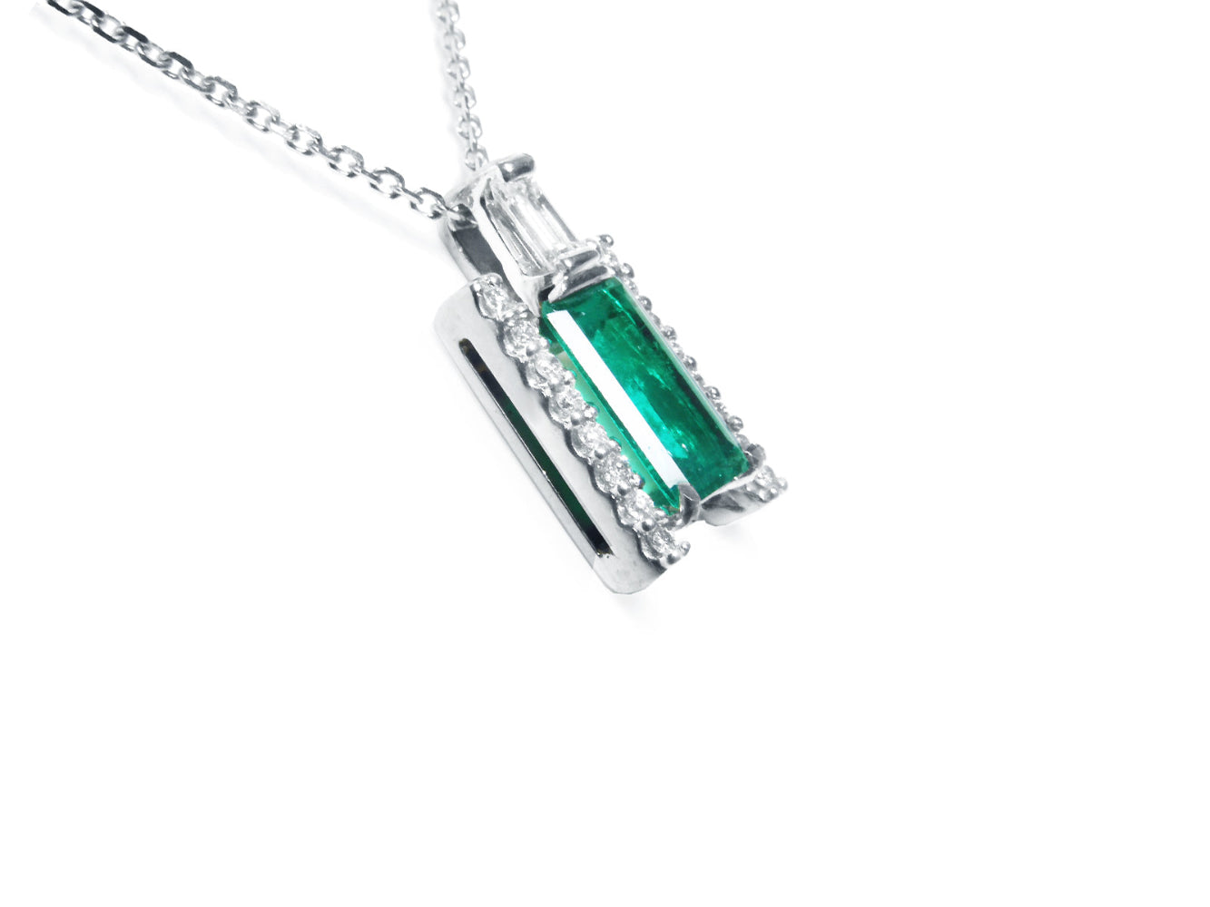 A white gold emerald baguette pendant with accent diamonds displaying the right-side gallery profile view.
