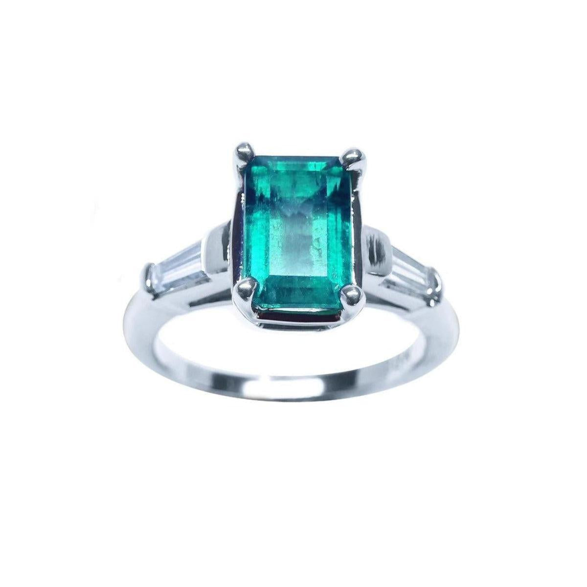 An emerald and baguette side diamond ring on a top and sides profile view with a white background