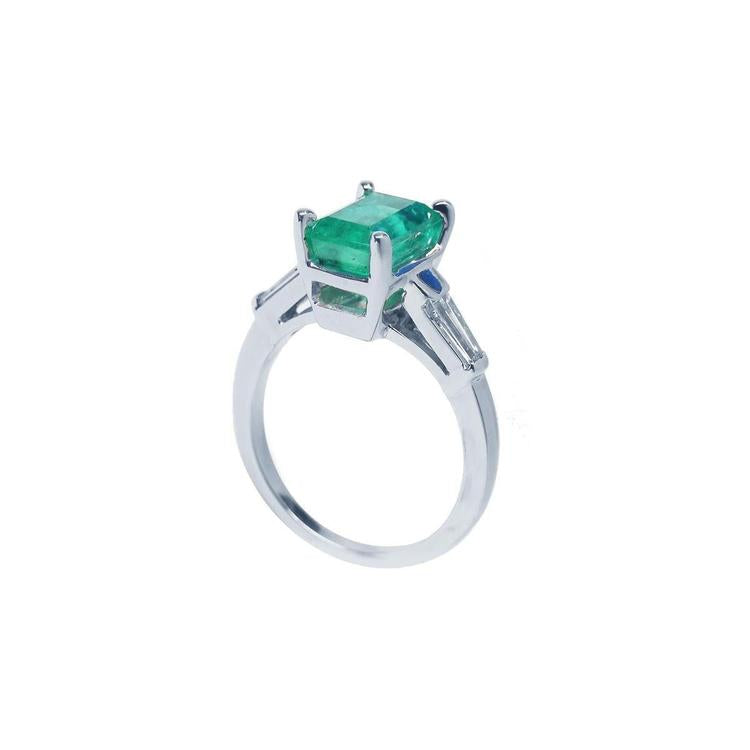 18K white gold ring with a rectangular deep bluish-green emerald and baguette side diamonds.