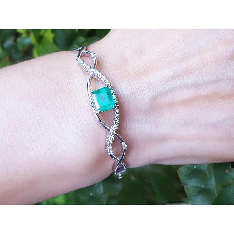 Emerald bangle bracelet for women enhanced by a entwines strip of near colorless natural diamonds 0.93 ct.