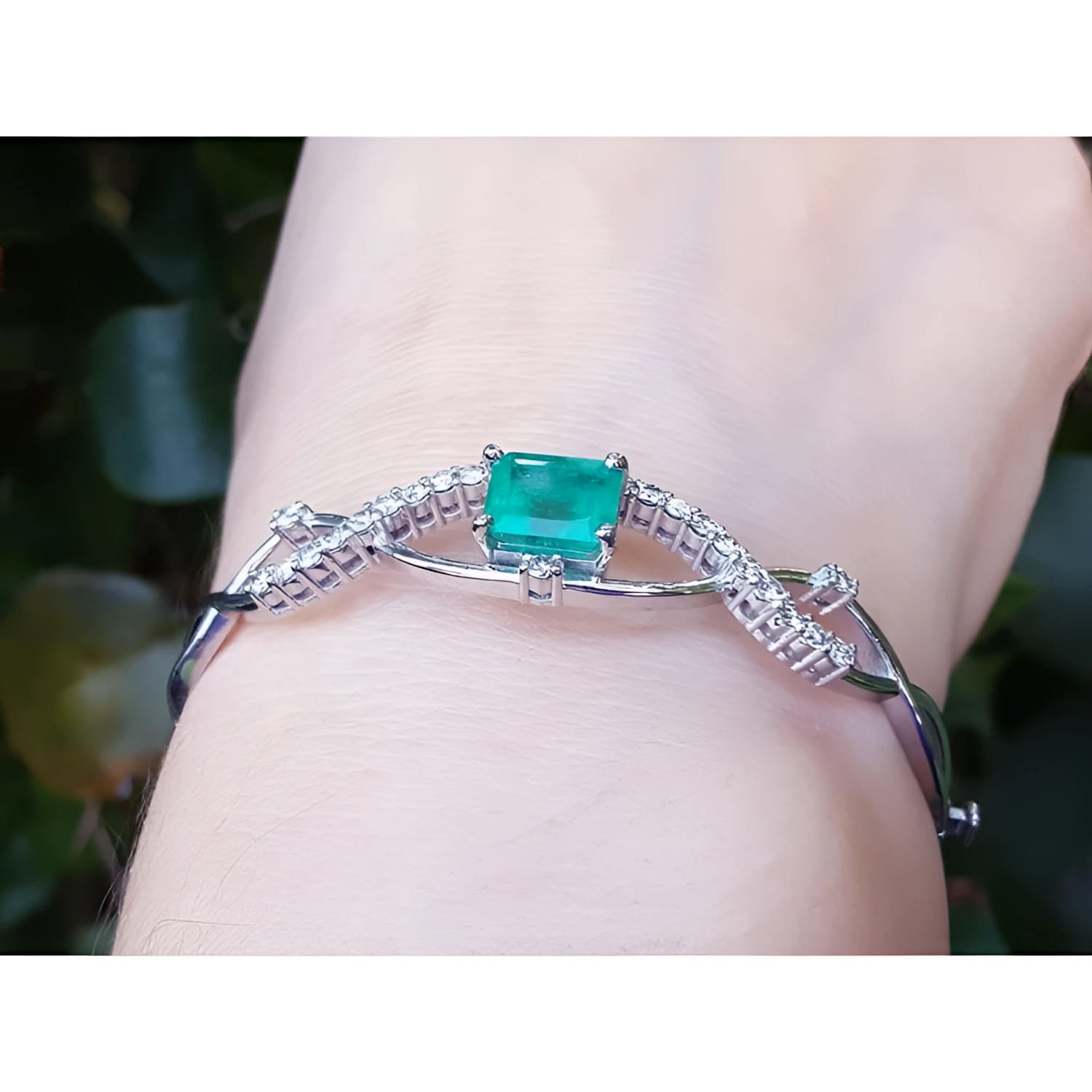 Emerald-cut emerald and natural diamond bangle bracelet in 14K white gold.