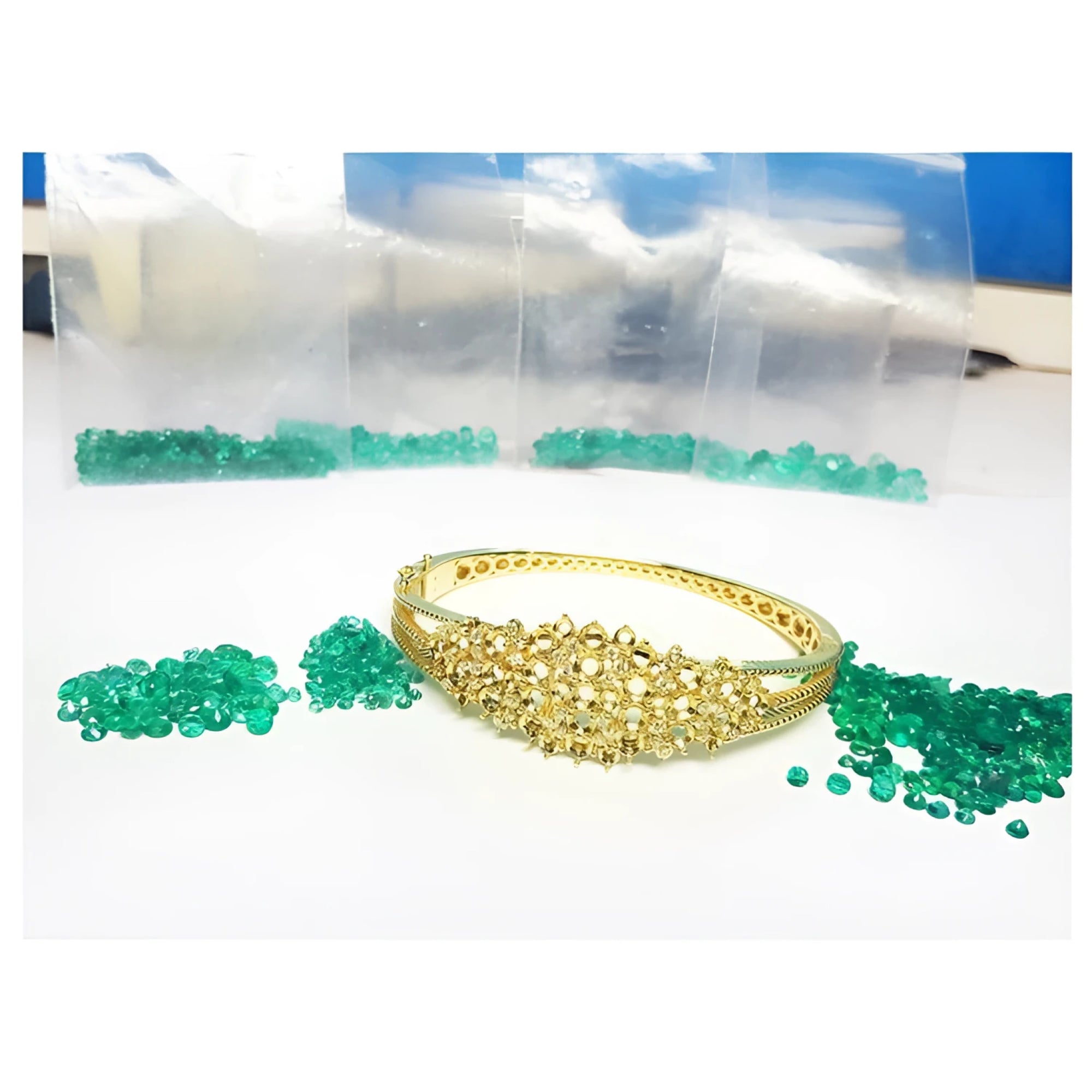 14K yellow gold bangle with round Colombian emeralds and diamonds in a floral design.