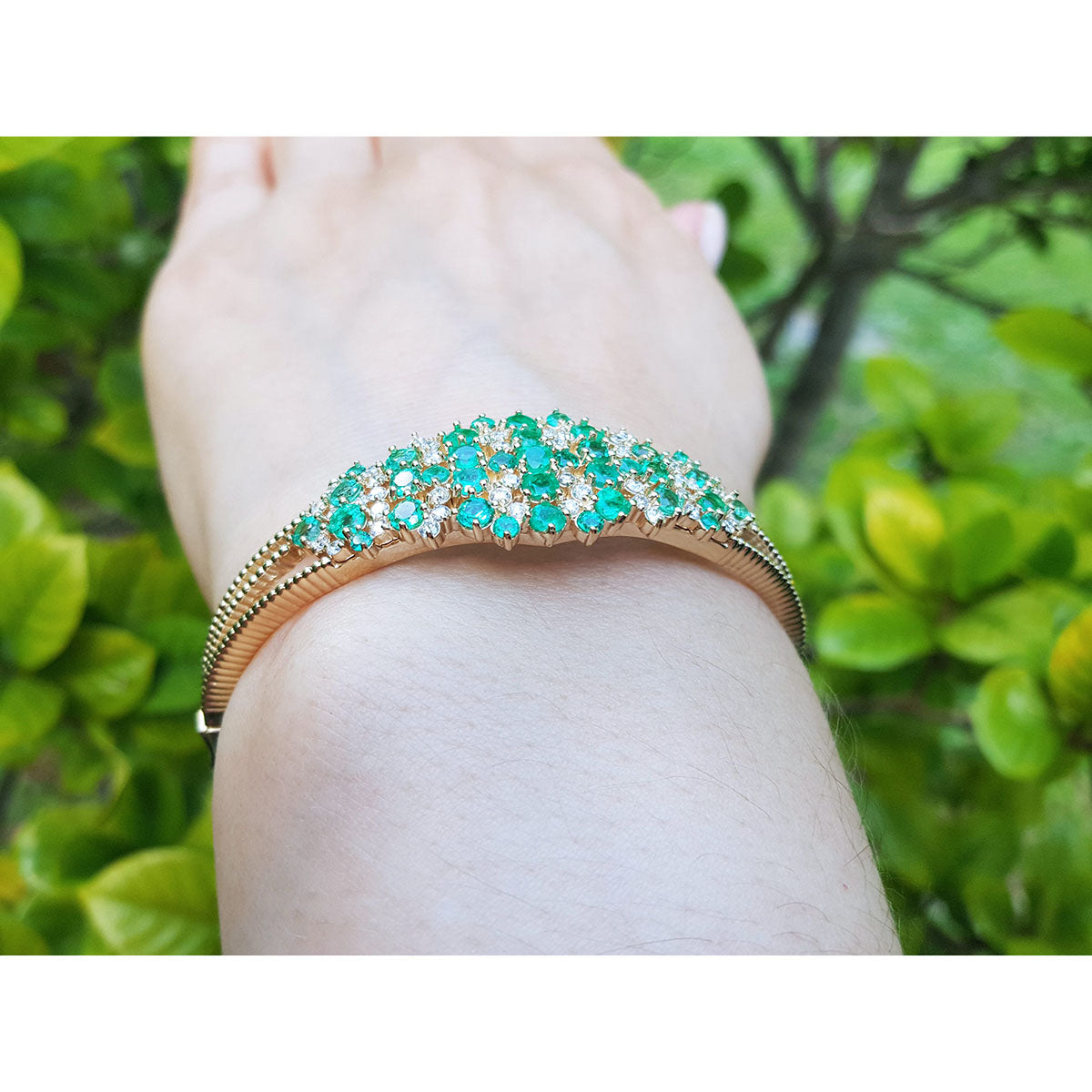 A side lateral view of a colombian emerald bangle bracelet on a wrist.