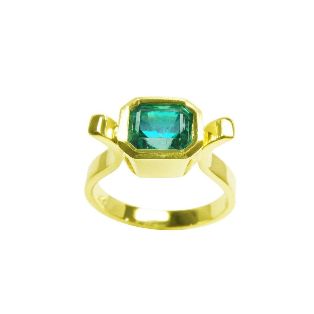 A topside view of a colombian emerald solitaire ring bezel set