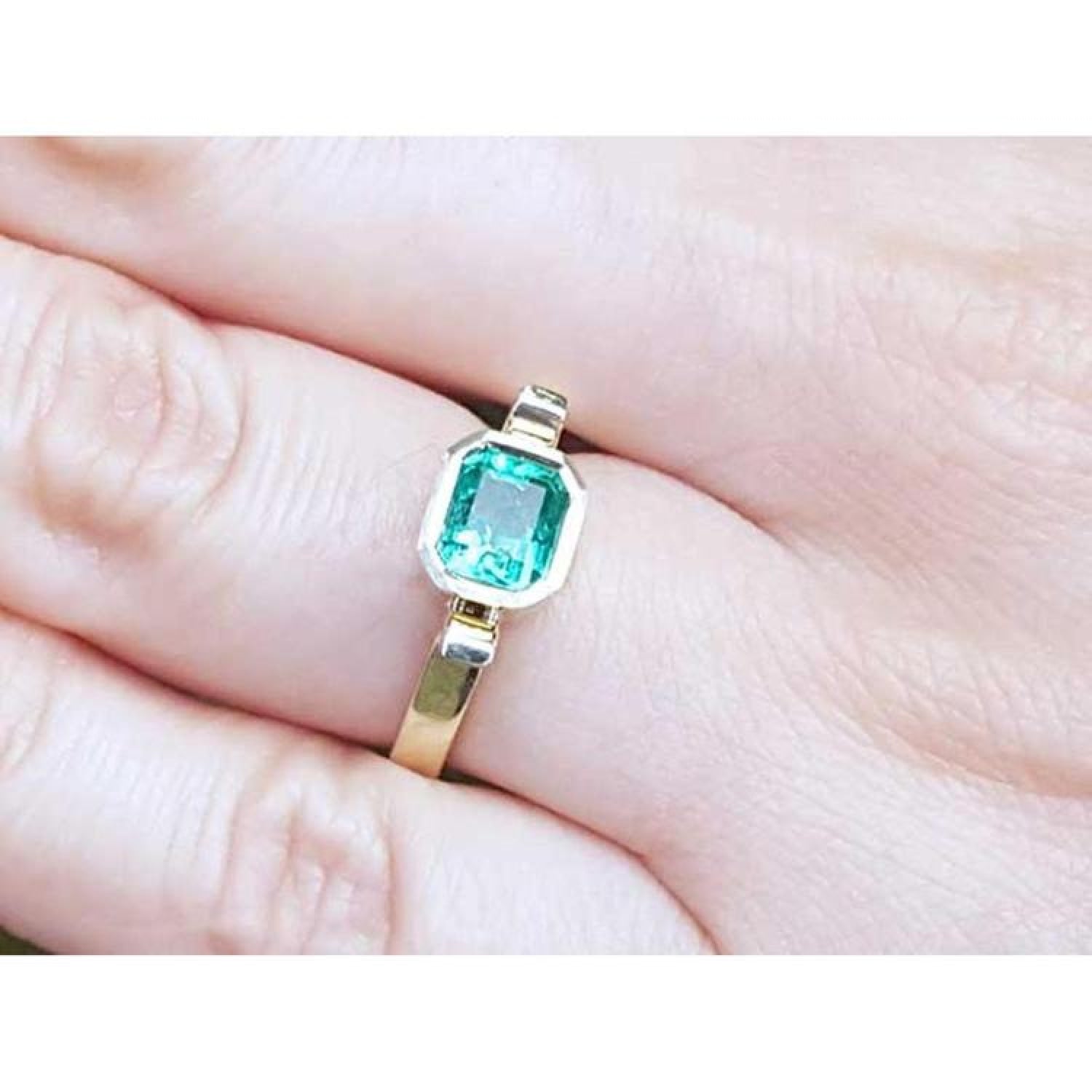 0.93 ct. solitaire Colombian emerald ring in 14K yellow gold, bezel set.