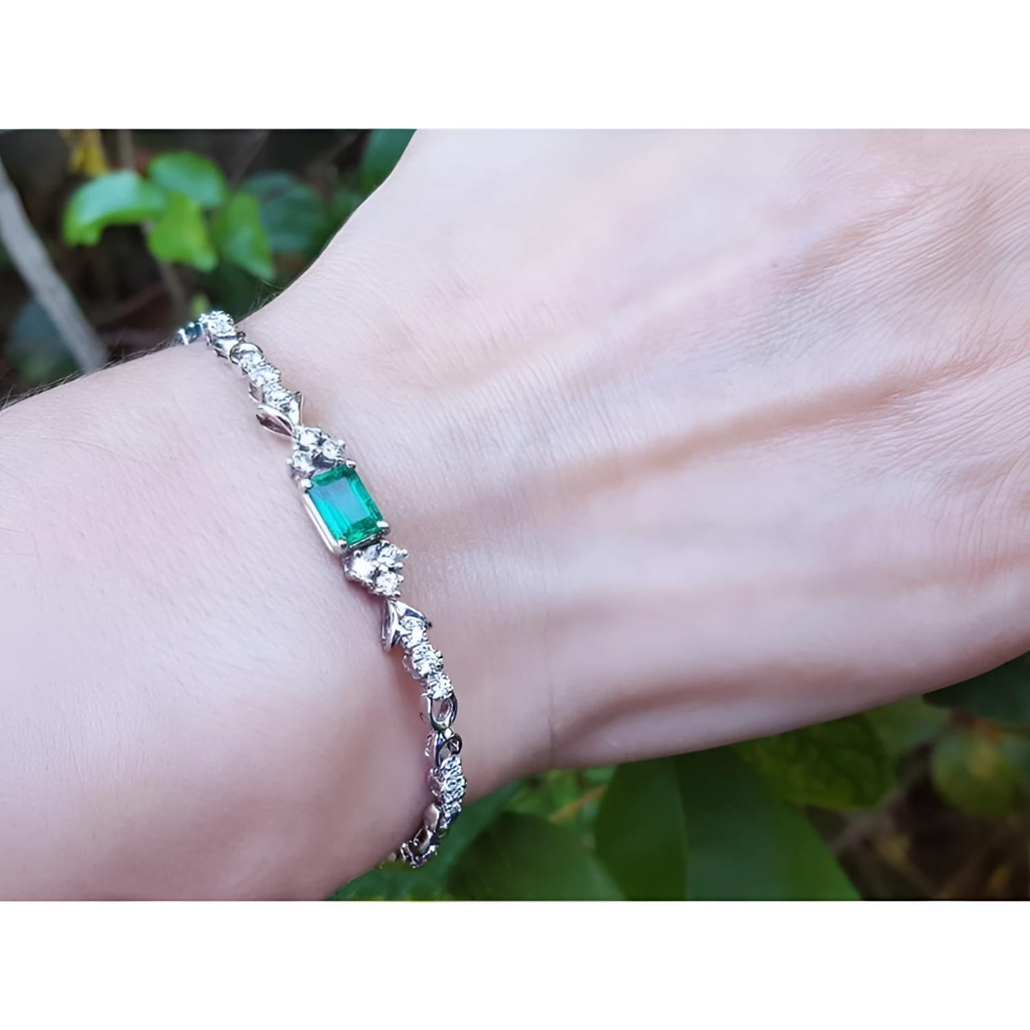 14K white gold bracelet with a rectangular Muzo Colombian emerald and diamond accents on a wrist.