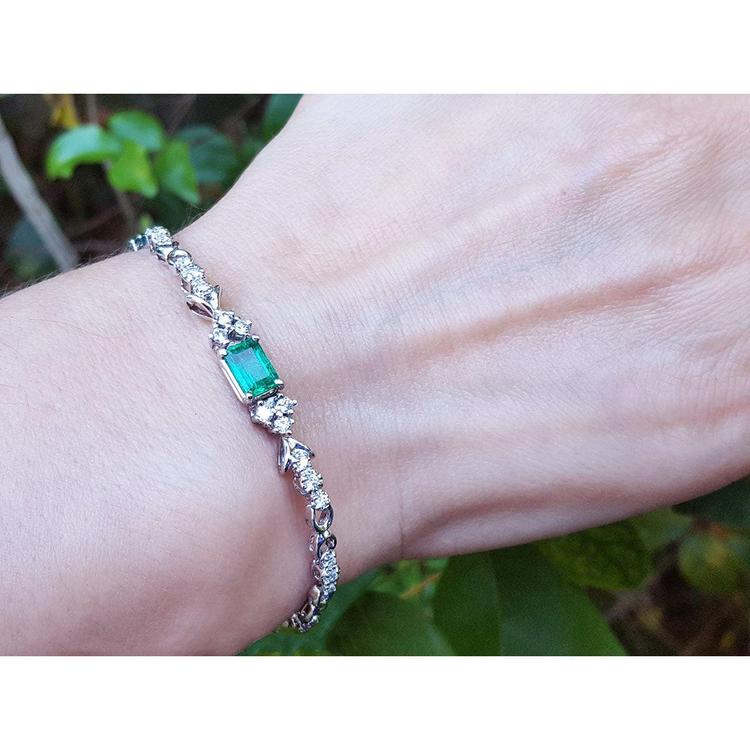 14K white gold bracelet with a rectangular Muzo Colombian emerald and diamond accents on a wrist.