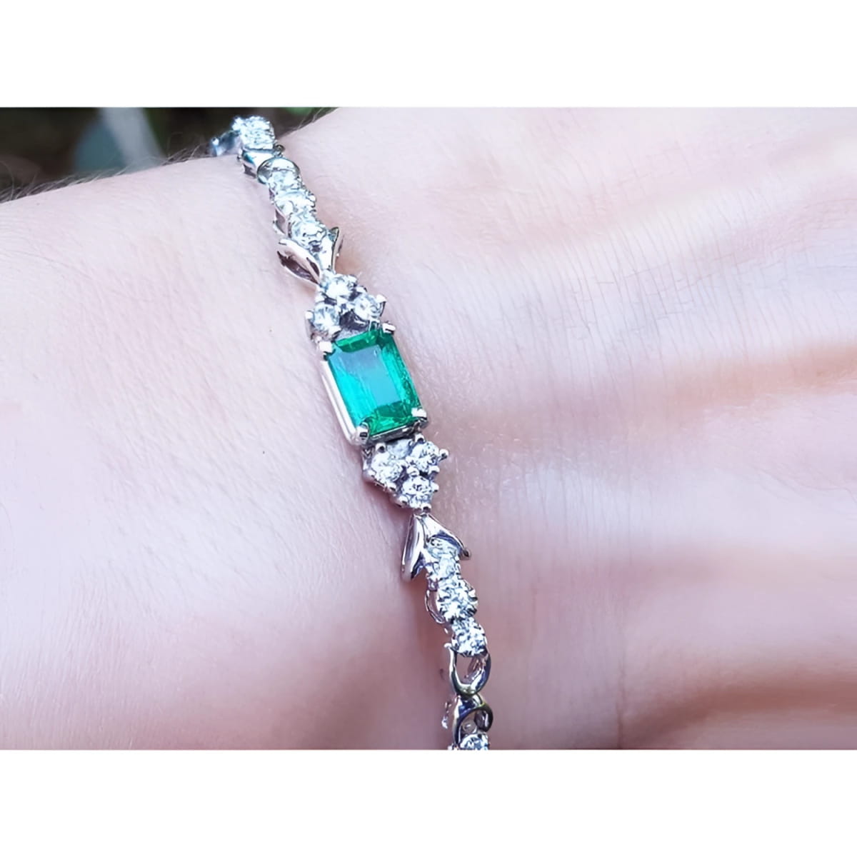 An emerald-cut Muzo Colombian emerald bracelet natural diamonds 14k white gold on a wrist.