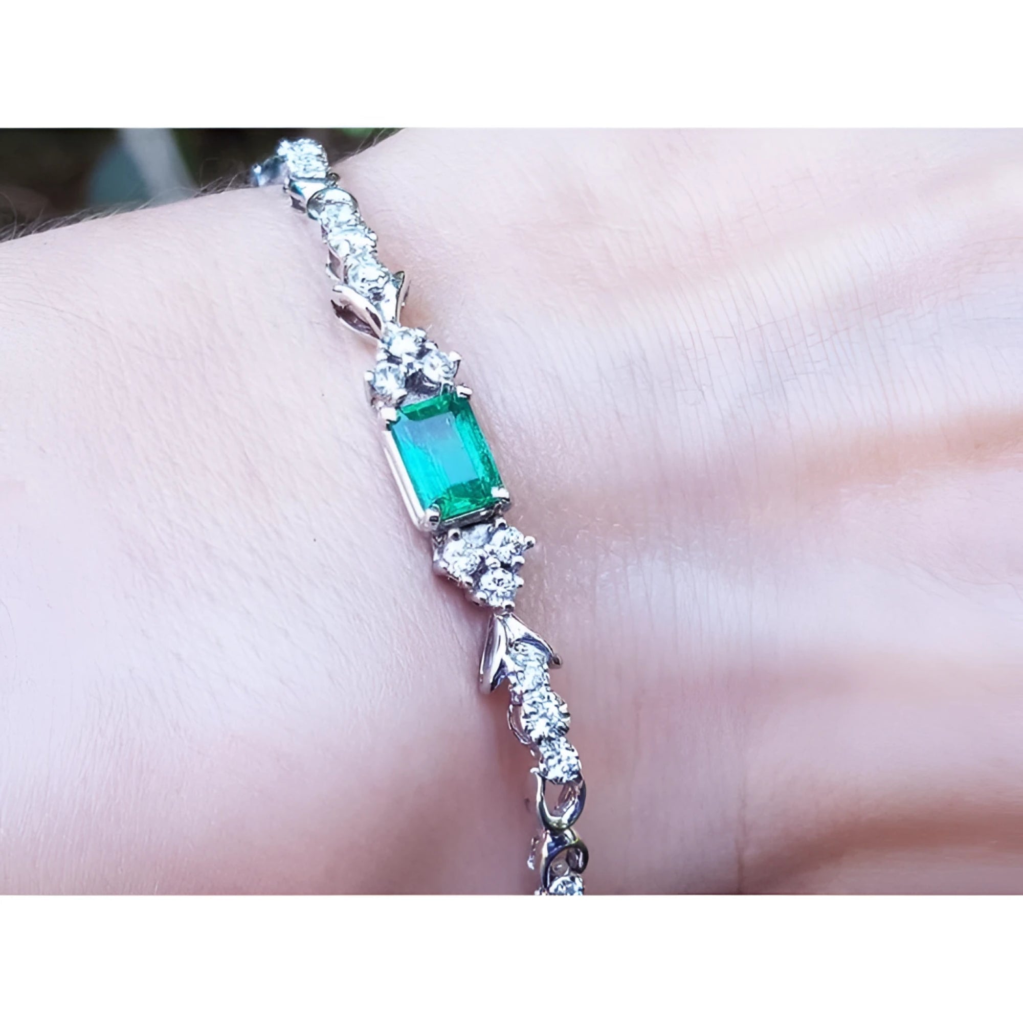 An emerald-cut Muzo Colombian emerald bracelet natural diamonds 14k white gold on a wrist.