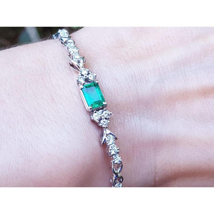 An emerald-cut Muzo Colombian emerald bracelet natural diamonds 14k white gold on a wrist.