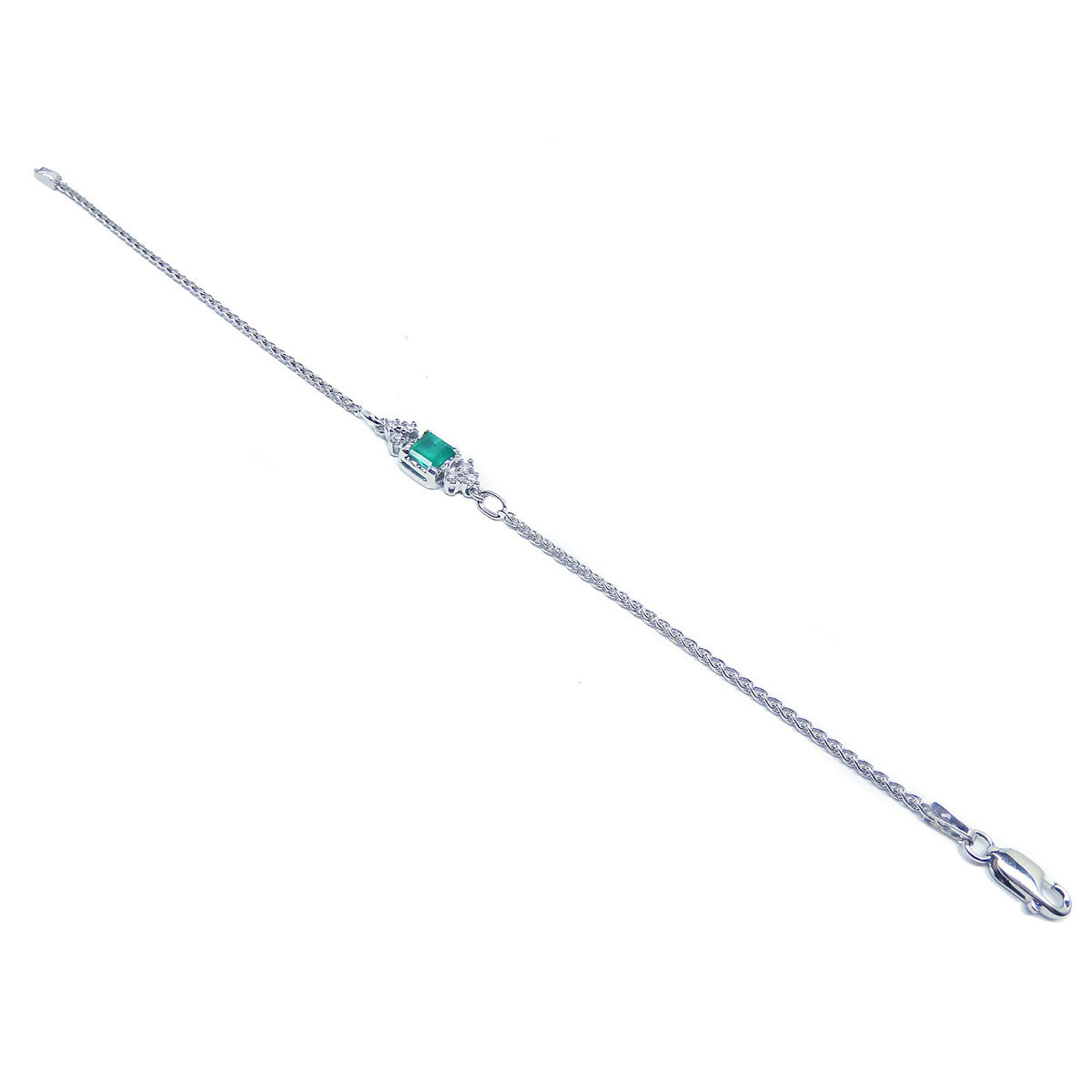 A distant view of a white gold emerald and diamonds bracelet on a white background