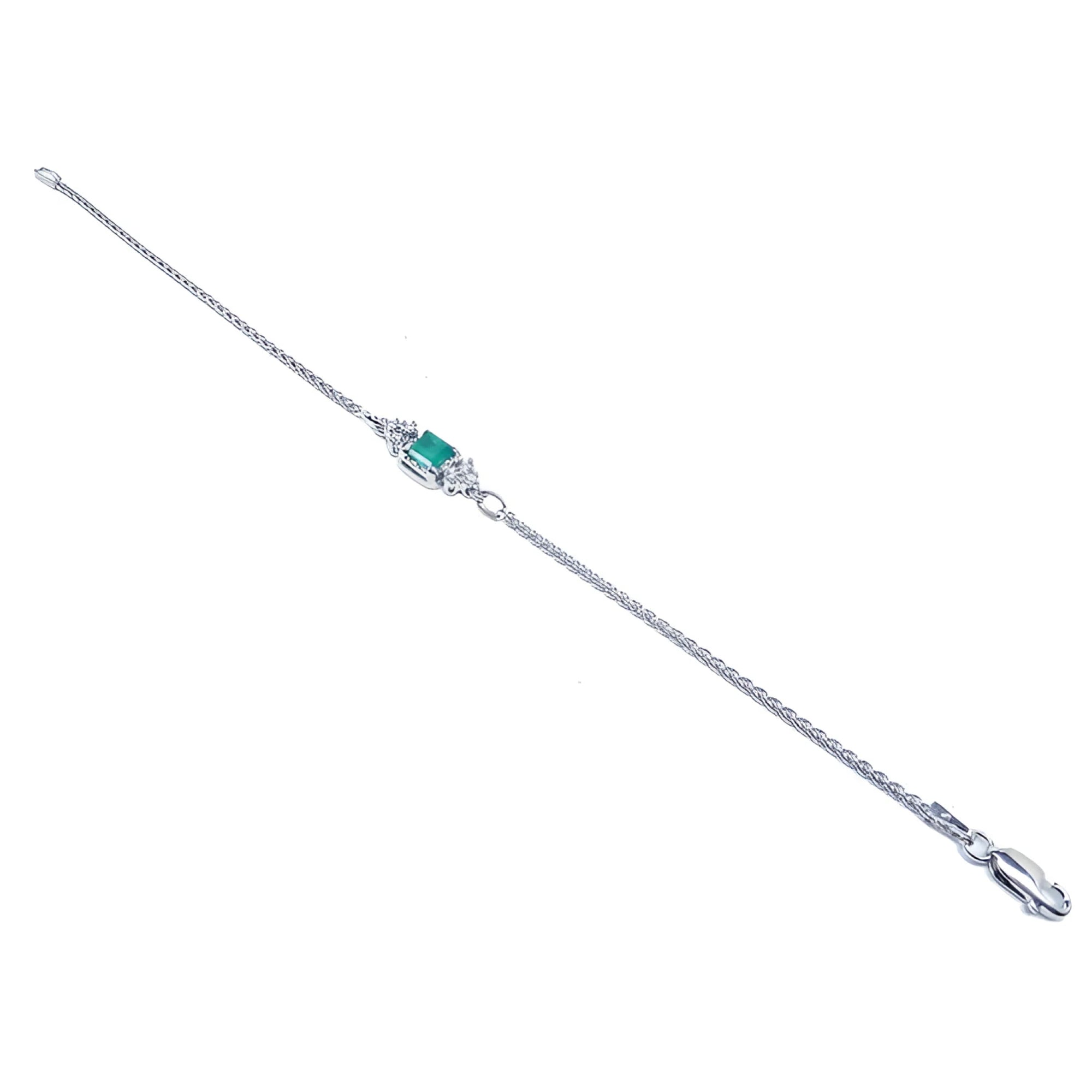 14K white gold bracelet with a central emerald-cut Colombian emerald and diamond accents.