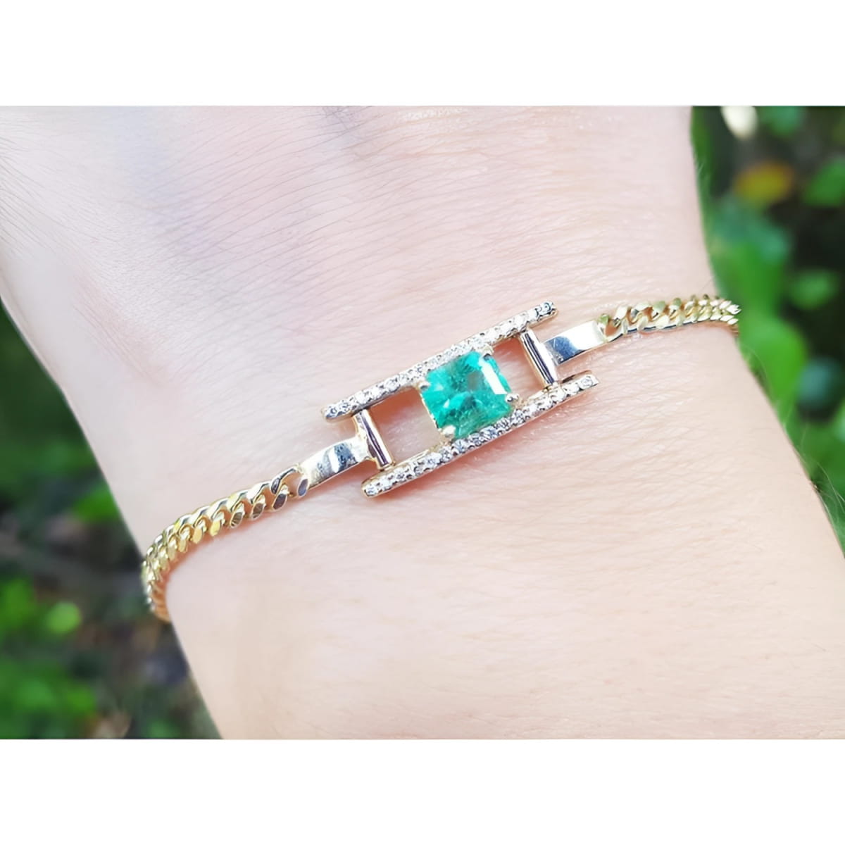 A 14k gold bracelet for women with a square natural emerald and diamonds displaying a vibrant medium-deep green color.