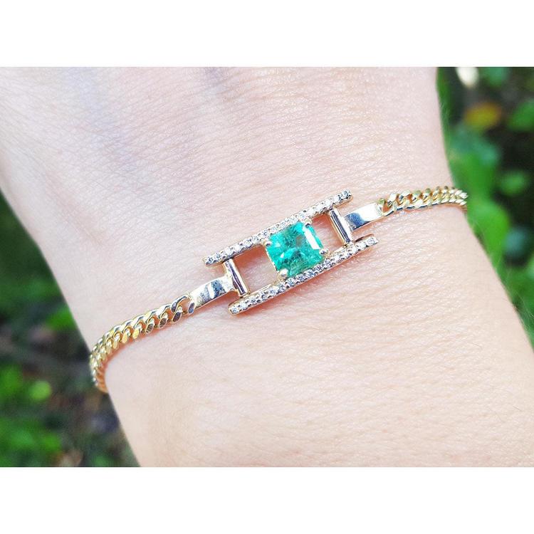 A 14k gold bracelet for women with a square natural emerald and diamonds displaying a vibrant medium-deep green color.