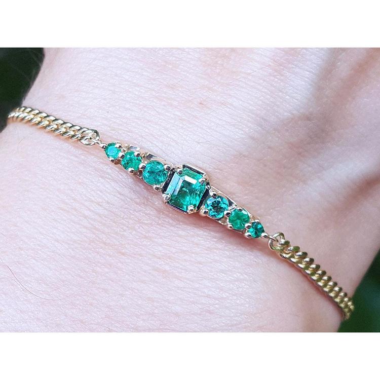 Lady’s bracelet featuring natural Colombian emeralds set in 14K yellow gold, showcasing sparkling medium deep green stones from the renowned Muzo mine.
