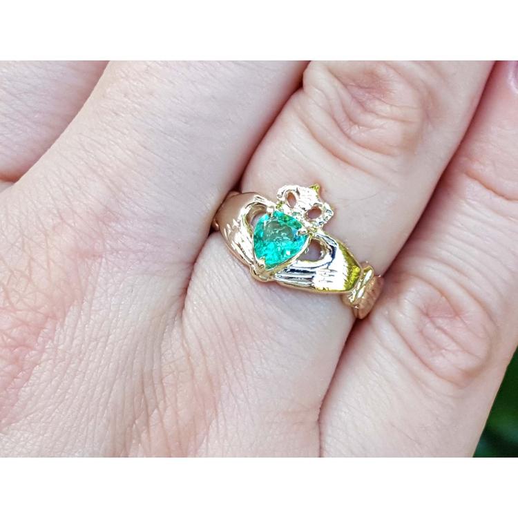 A natural colombian emerald claddagh ring on a person's finger.
