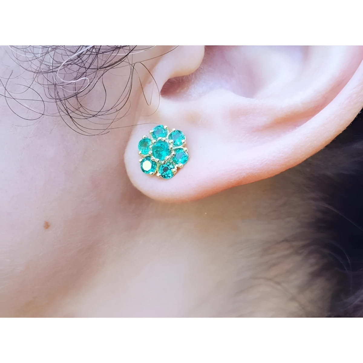 Close-up of an ear wearing a natural emerald cluster earring.