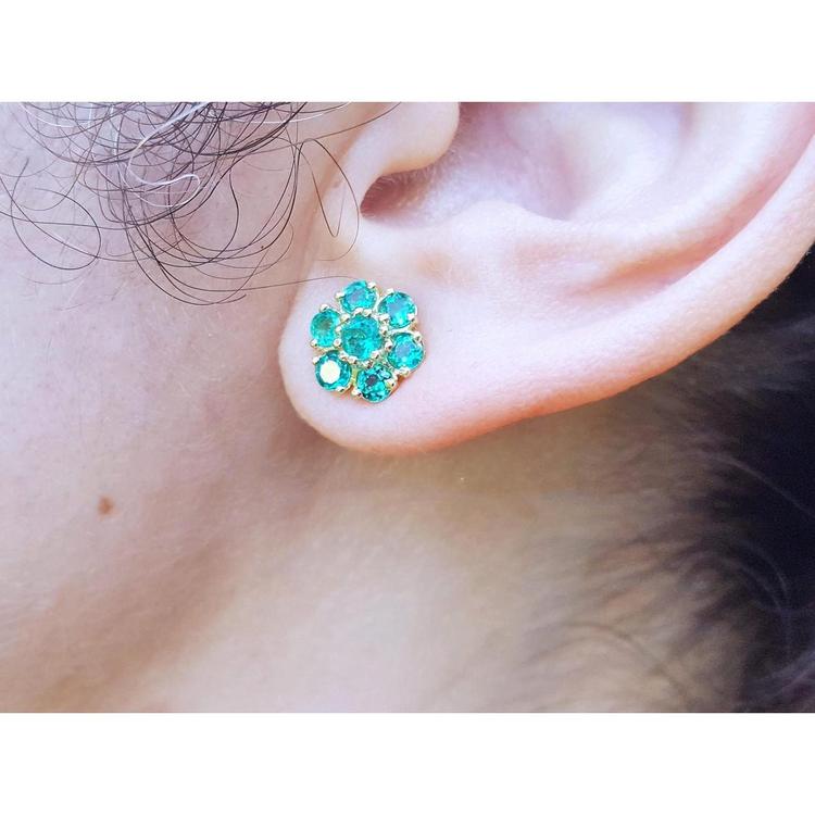 Close-up of an ear wearing a natural emerald cluster earring.