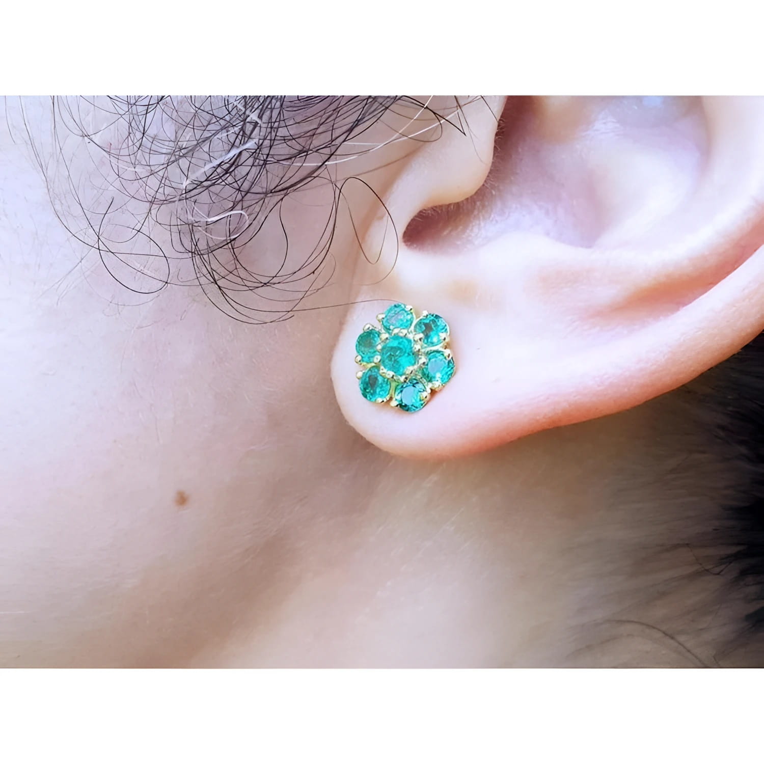 18K yellow gold stud earring with six round-cut natural Colombian emerald petals, worn on an ear.