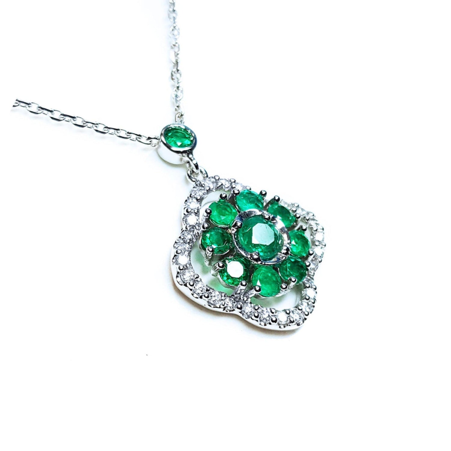 A 14k white gold necklace with genuine round cut colombian emeralds cluster pendant.