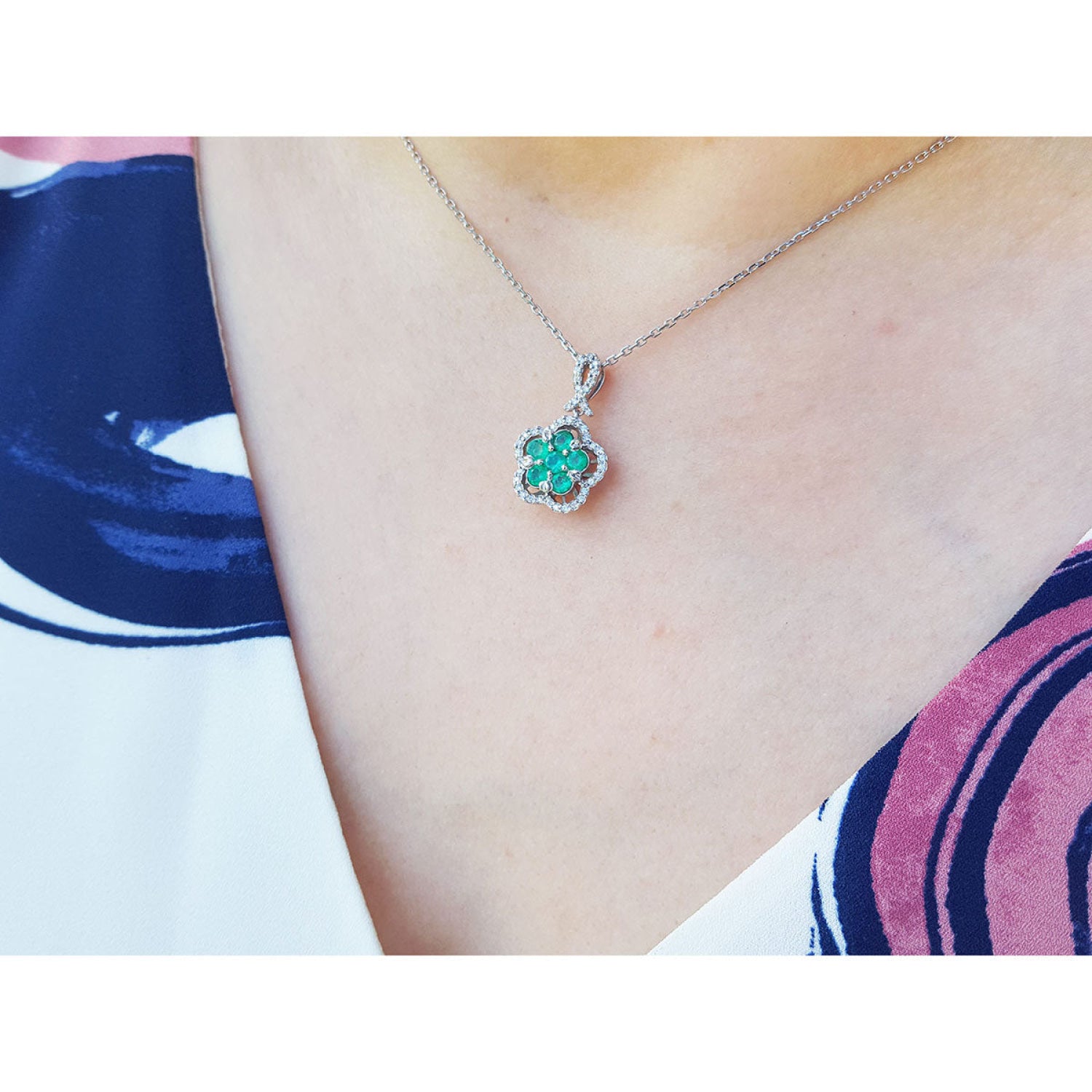 Emerald cluster necklace with diamonds in 14K white gold, clover-like design on a woman's neck.