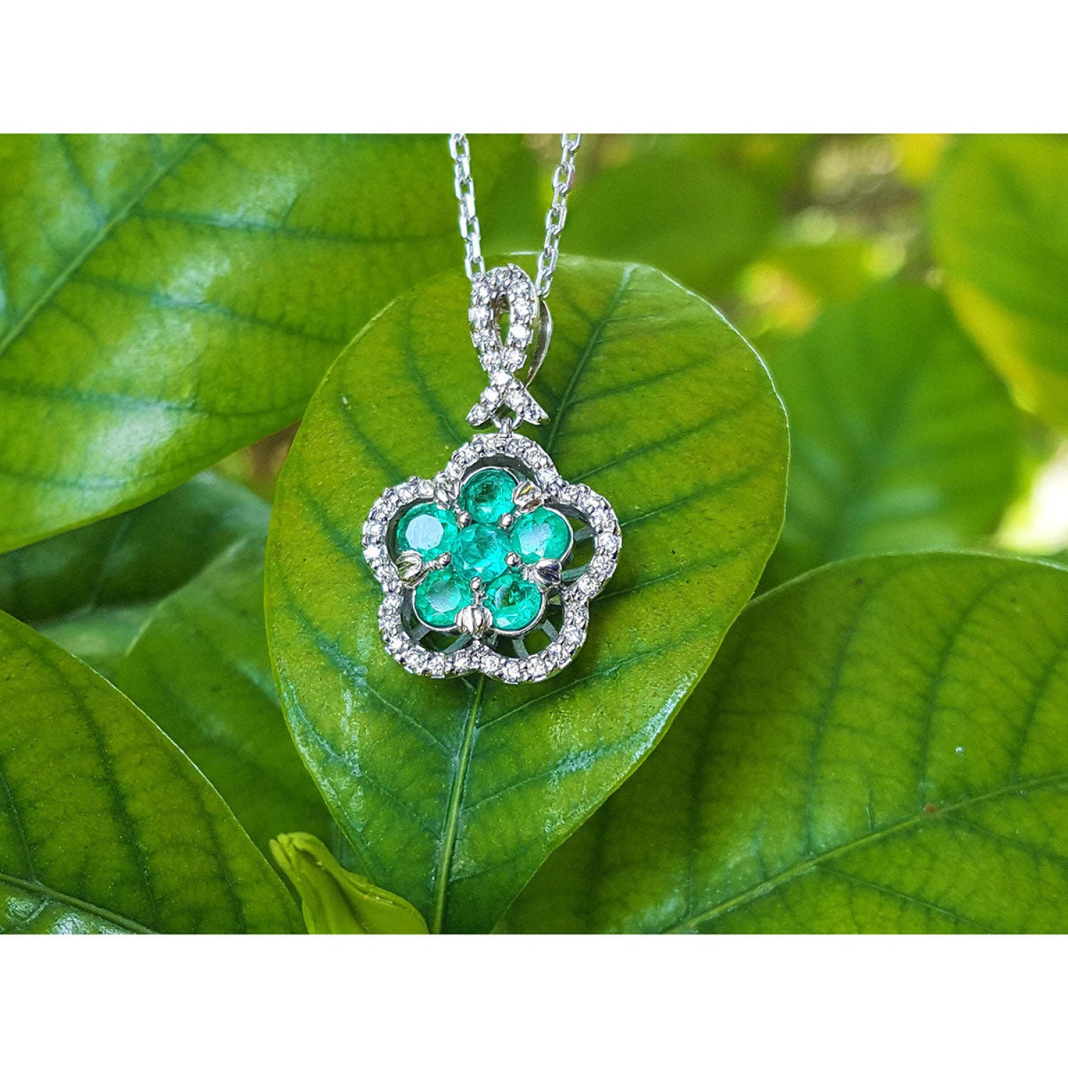 Emerald cluster necklace with round cut emeralds and diamonds in 14K white gold, clover-like design.