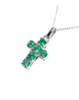 A genuine Muzo mine colombian round cut emerald cross pendant dangling from a 14k white gold necklace. 