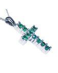 An emerald cross pendant necklace with round cut Colombian emeralds, set in 18k white gold.