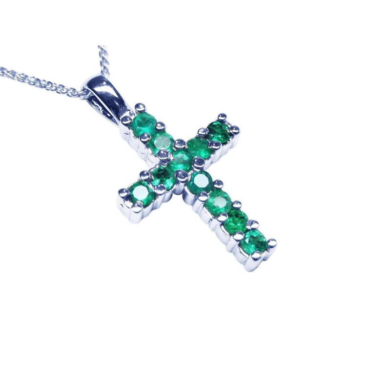 A 18k white gold cross pendant with round cut Colombian emeralds on a topside view position.