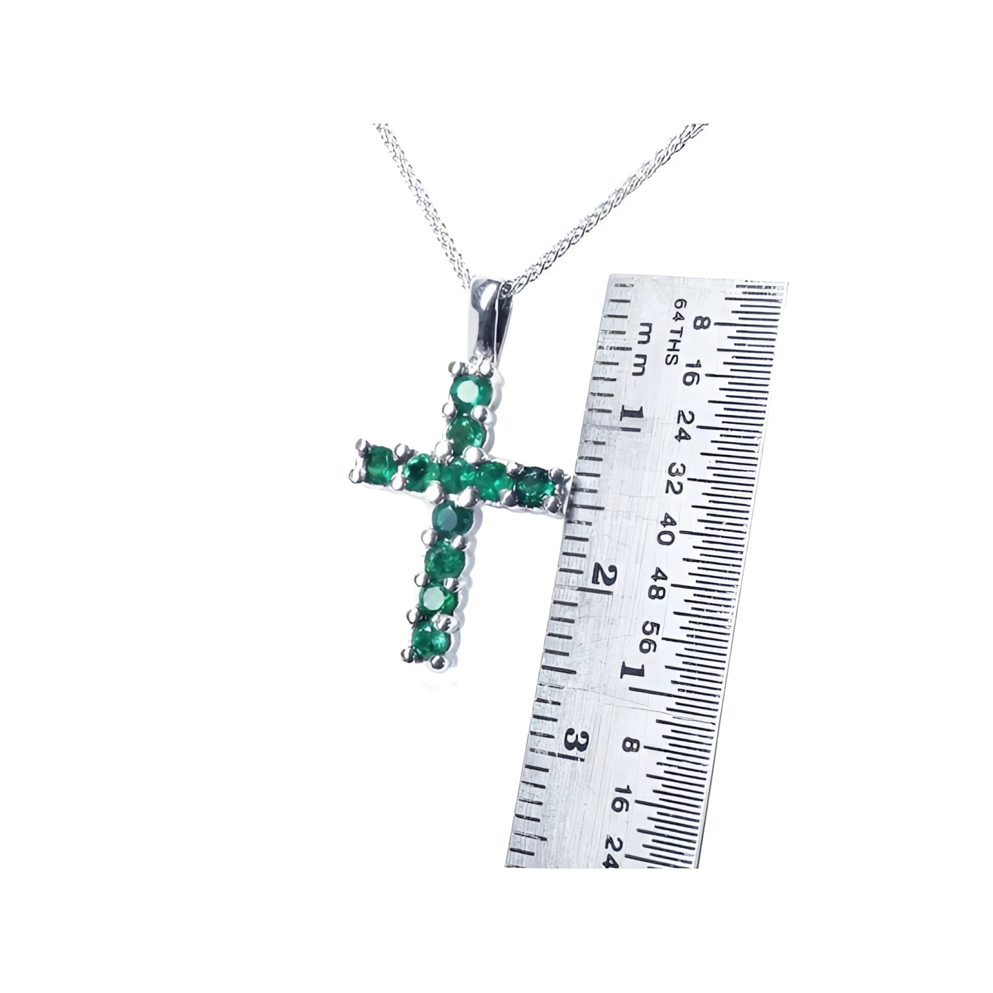 Round-cut emerald cross pendant necklace in 18K white gold, shown with a ruler for size.
