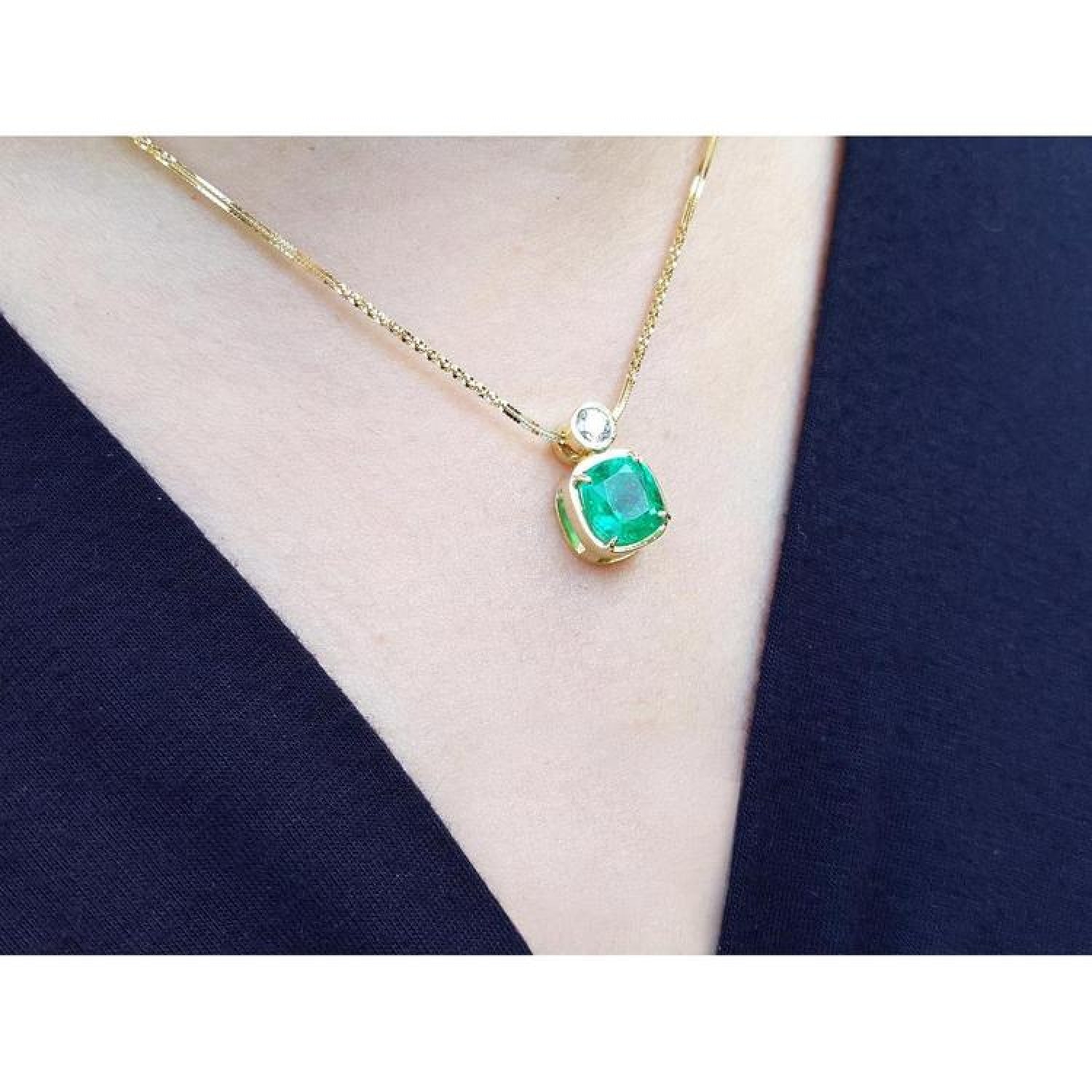 Vibrant 3.43 ct. cushion-cut emerald pendant in 18K yellow gold with a small diamond accent.