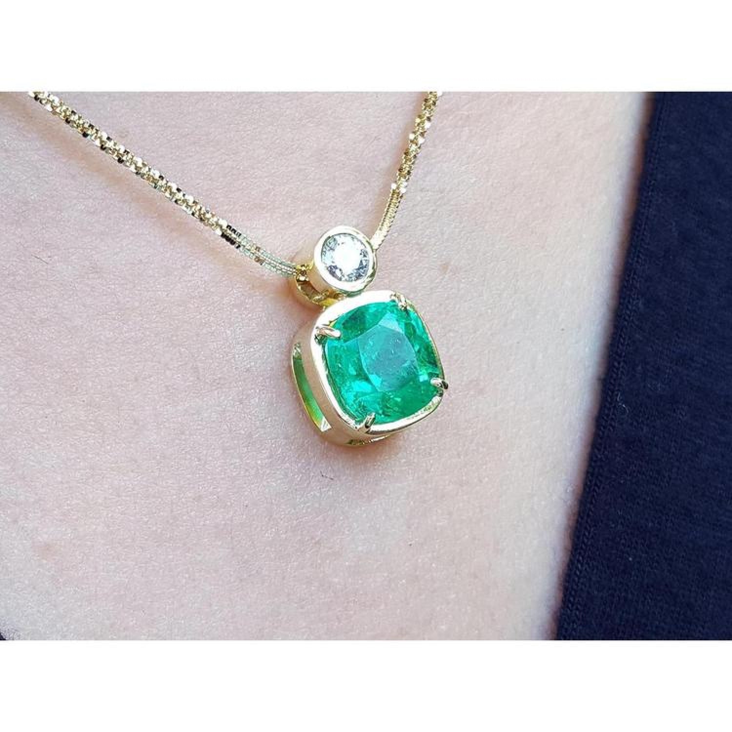 3.43 ct. emerald cushion cut pendant with a diamond accent in 18K yellow gold on a gold chain.
