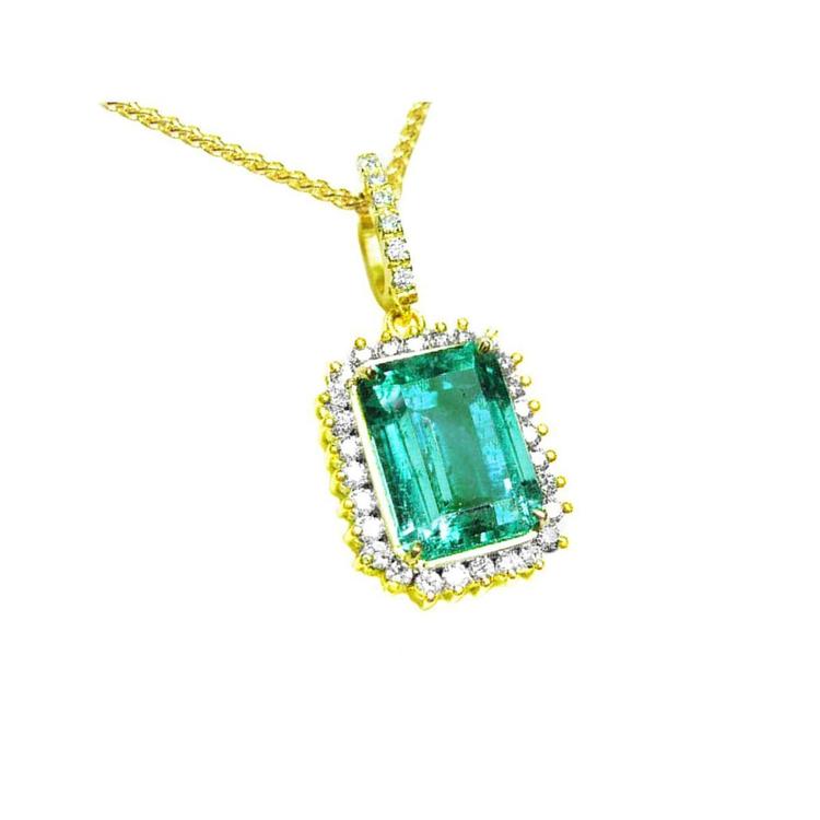 
the topside view of a natural colombian emerald pendant emerald-cut surrounded by a halo diamond in 18k yellow gold.