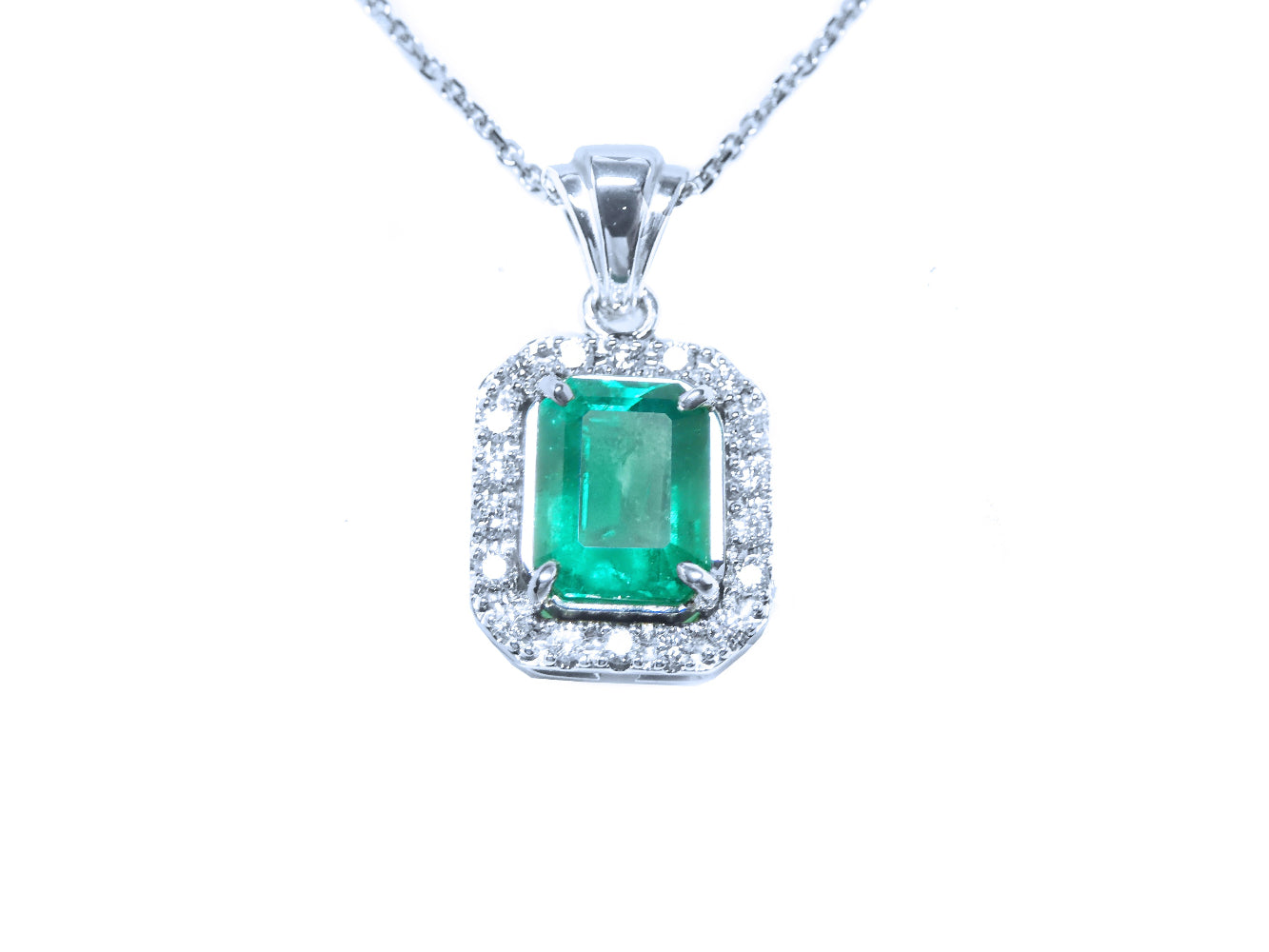 Emerald pendant with diamond accents on a white background