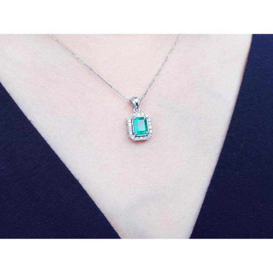 Emerald-cut emerald pendant with halo diamonds in 14K white gold, worn on a model.
