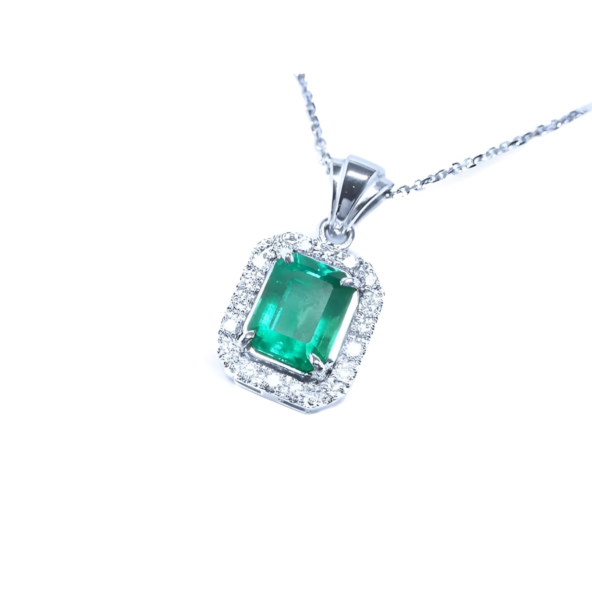 Emerald-cut Colombian emerald pendant with halo diamonds in 14K white gold.