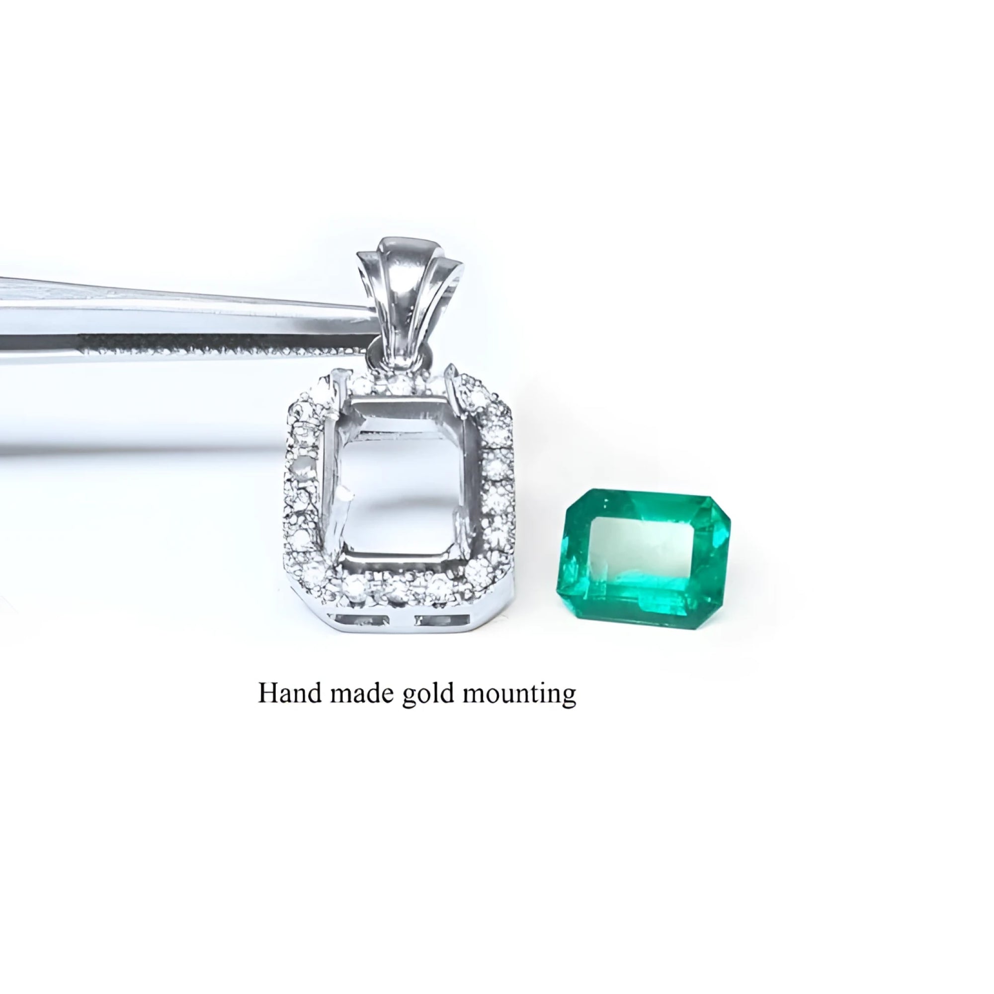 14K white gold halo diamond pendant mounting next to a loose emerald-cut Colombian emerald.