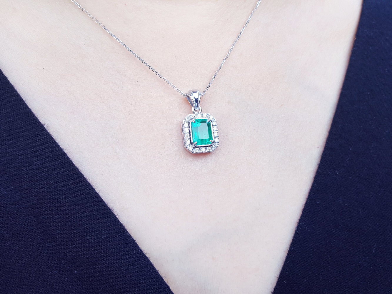 Emerald pendant necklace on a person&#39;s neck.