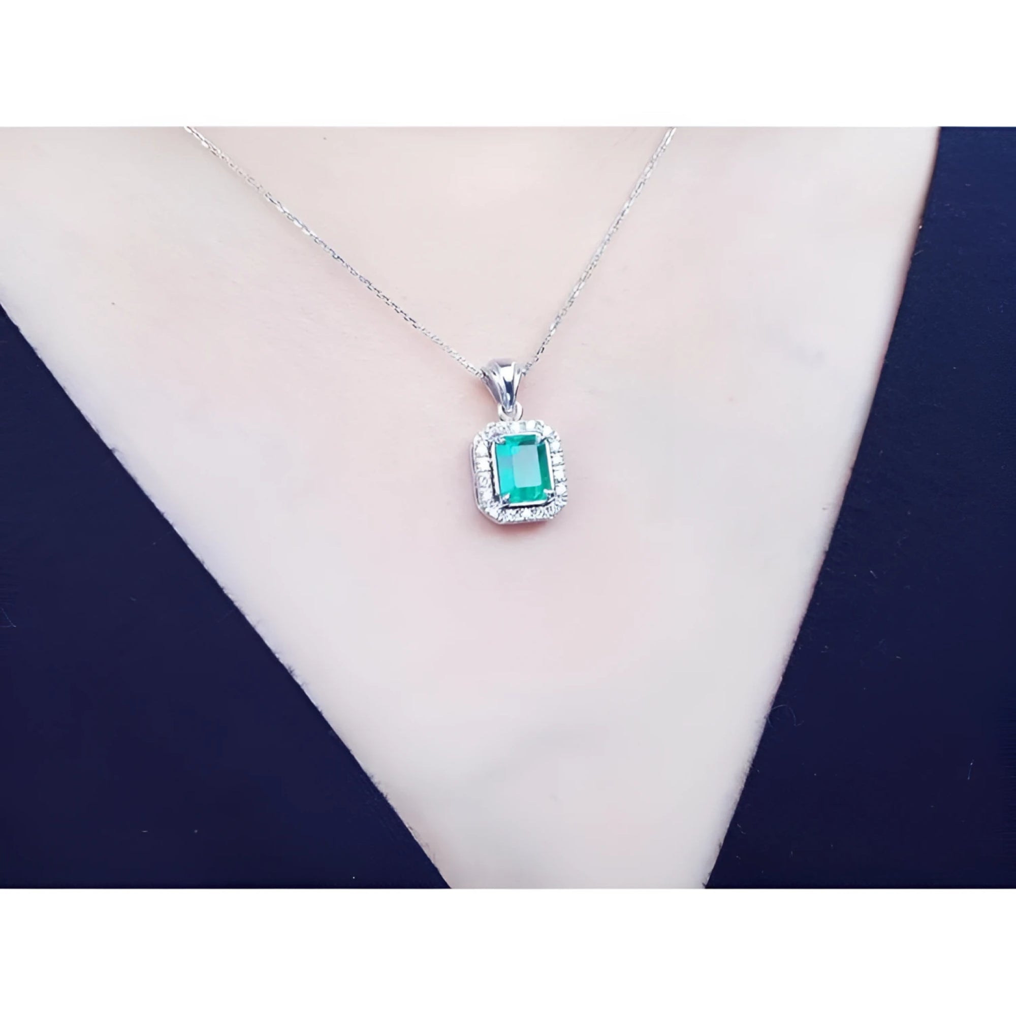 Emerald-cut emerald pendant with halo diamonds in 14K white gold, worn on a model.