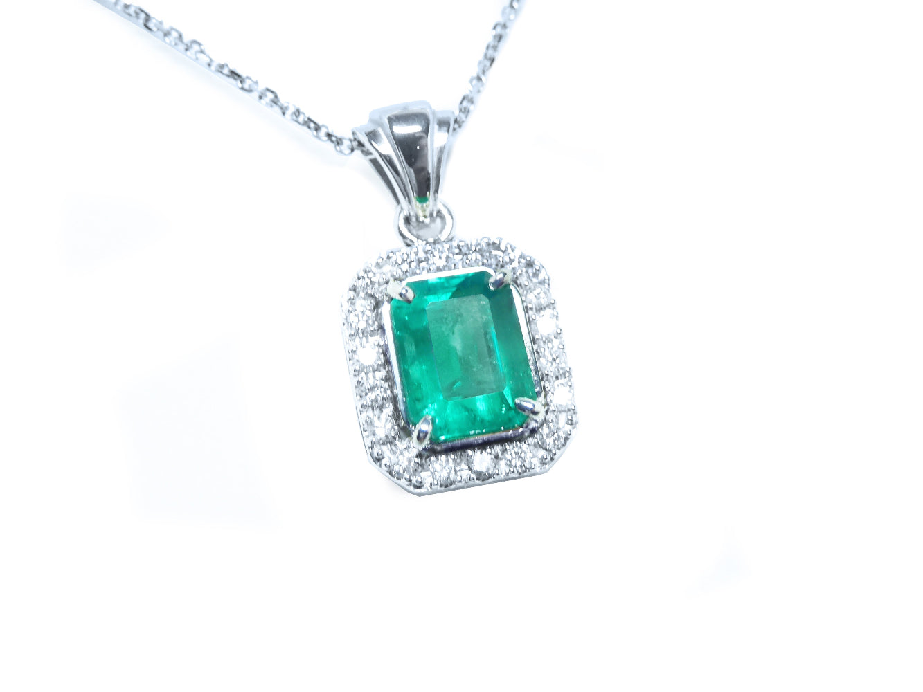 Emerald-cut emerald gemstone pendant with diamond accents on a topside view position.